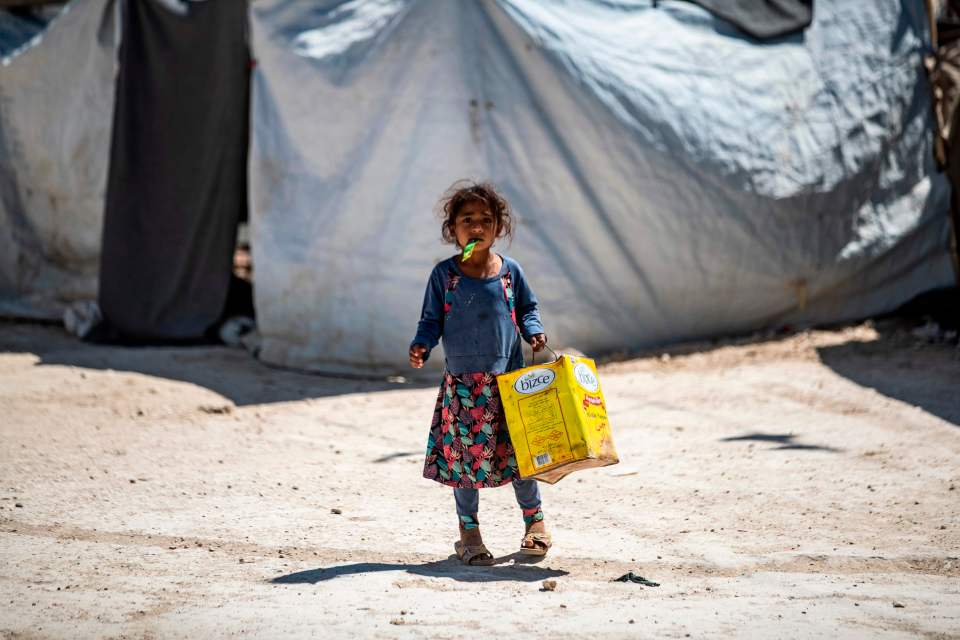  A displaced Syrian girl carries a container in the al-Hawl refugee camp