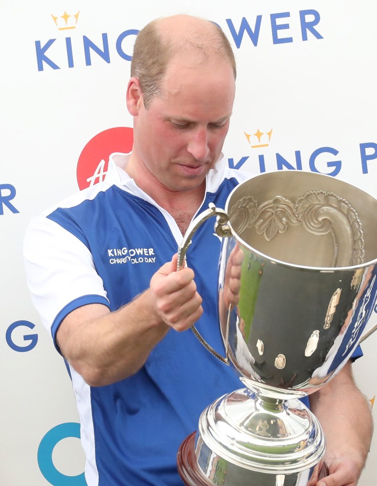 Prince William studies a trophy during a presentation at the King Power Royal Charity Polo Day