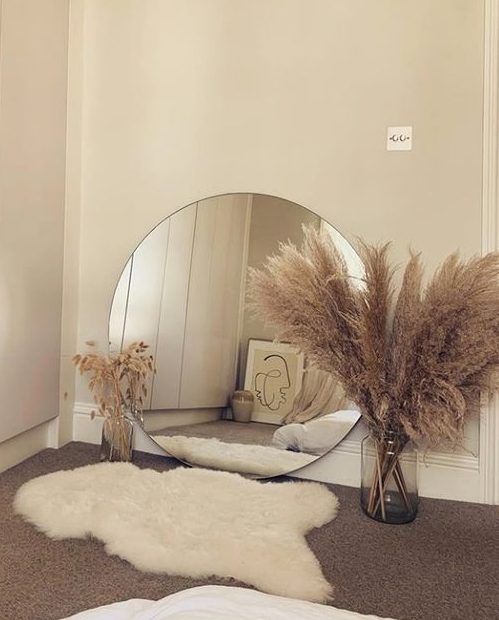  A round mirror sits on the floor alongside yet more foliage