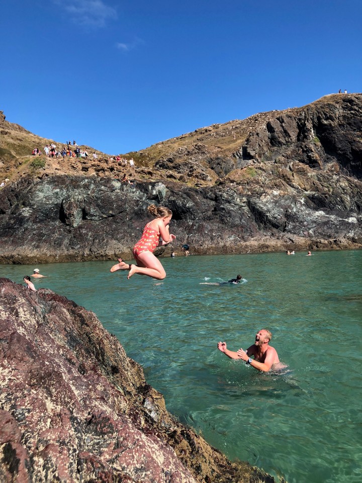  Lottie Wykes leaps into crystal clear waters (and the arms of dad Sam) at Kynance Cove, Cornwall