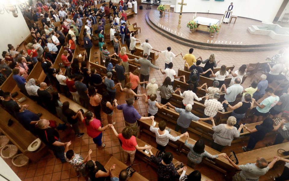  People hold hands during a vigil for victims at St Pius X Church in El Paso