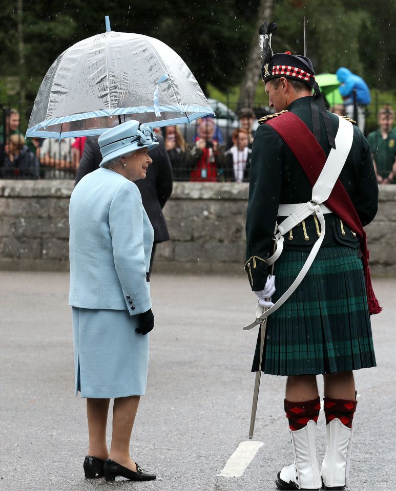 The monarch kept dry with an umbrella that matched her blue outfit