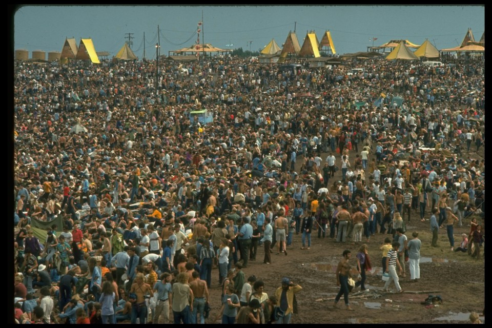  Overall shot of the huge crowd, looking towards the large yellow tents during the Woodstock Music & Art Fair