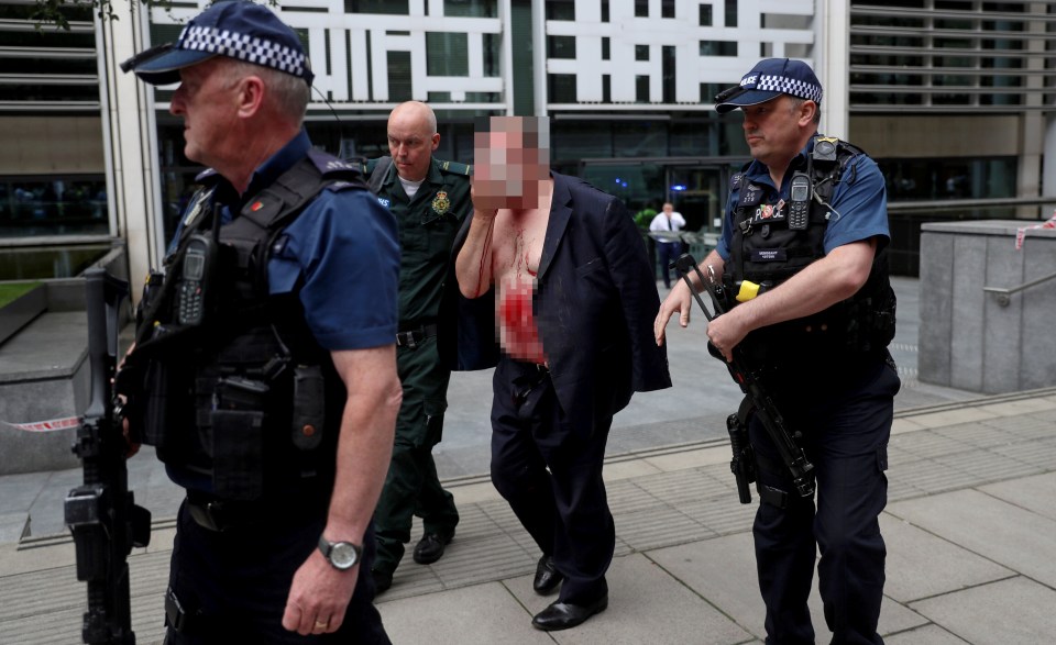 A civil servant is seen with blood pouring from his face amid armed police who swooped at the Home Office after a knife attack