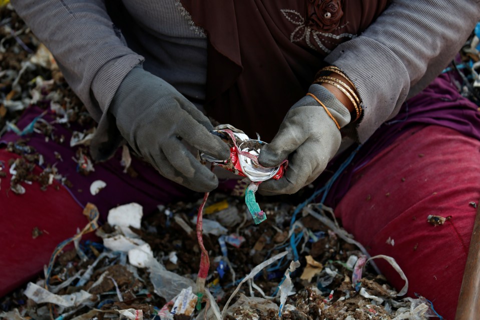  Kusmani, a 55-year-old woman who has been a scavenger for more than 20 years, holds a used can as she sorts rubbish at Bangun