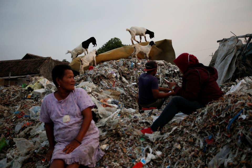  Sunarni sits on a pile of rubbish as her son-in-law sorts through it