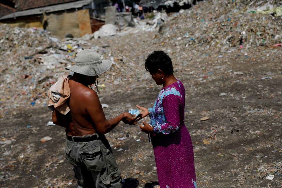  Sunarni receives money from a scavenger after they unloaded rubbish