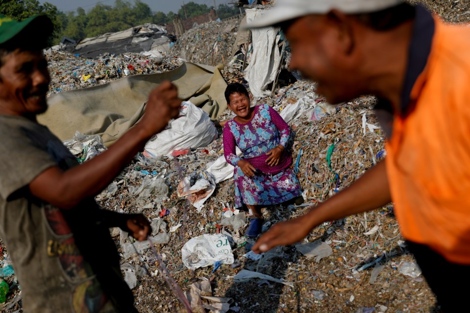  Sunarni laughs as her husband Salam jokes with his friend near a pile of rubbish at Bangun