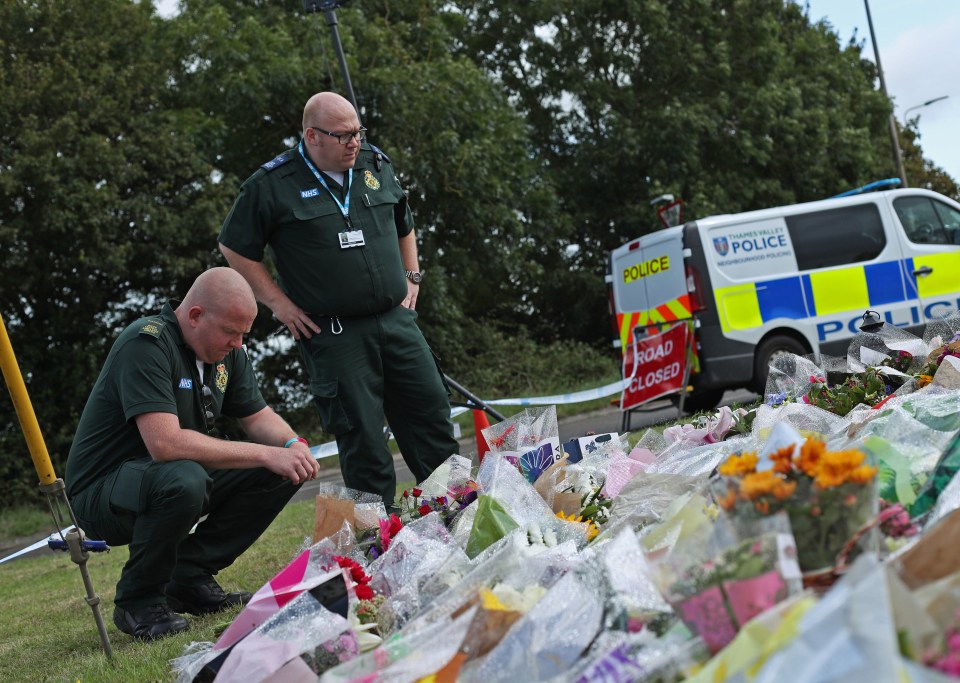 Paramedics pay their respects to PC Harper in front of floral tributes at Ufton Lane, Berkshire