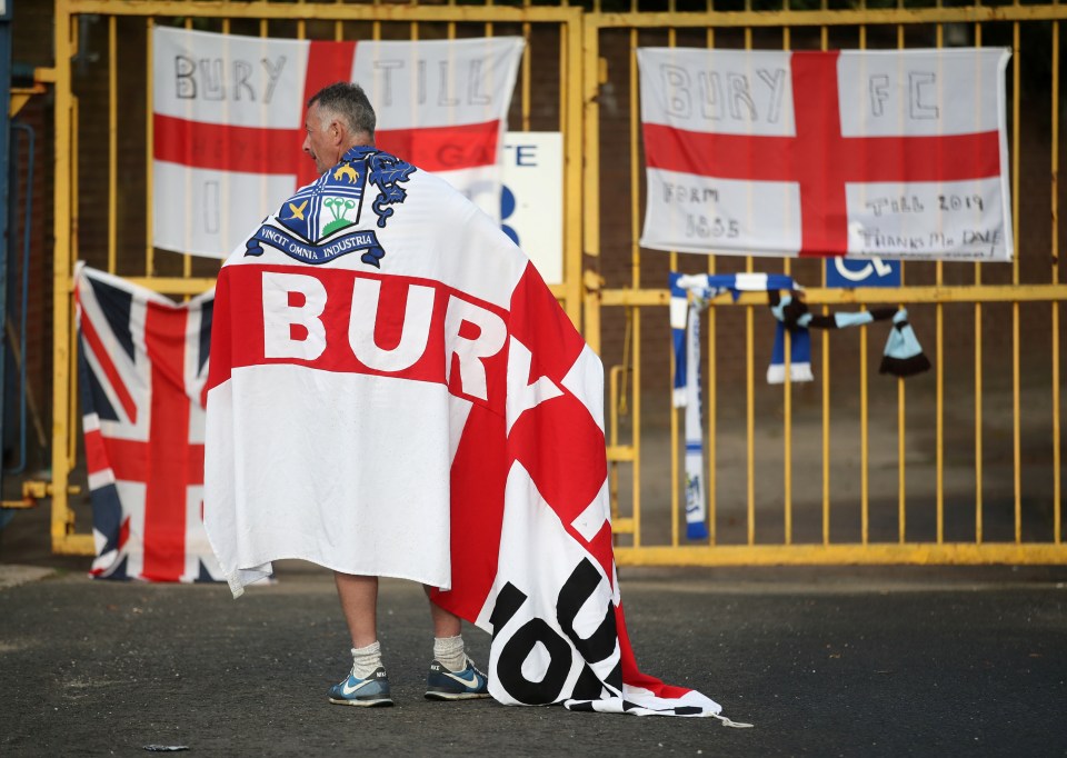  A Bury fan outside their ground Gigg Lane on the day they were expelled from the Football League - but the Shakers could yet be saved