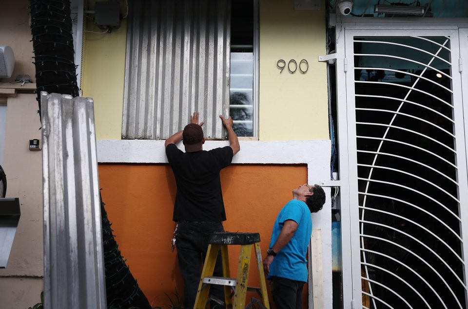  A Miami Beach resident places a hurricane shutter over a window as he helps prepare a business for the possible arrival of Dorian