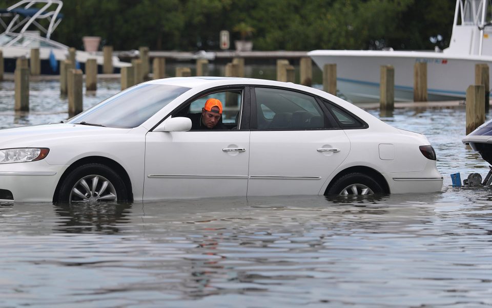  A Miami resident drives through a flooded parking lot - the city is experiencing high tides ahead of Dorian