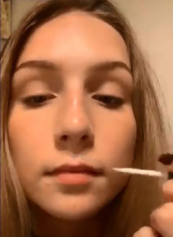 The girl begins by adding superglue to just above her top lip