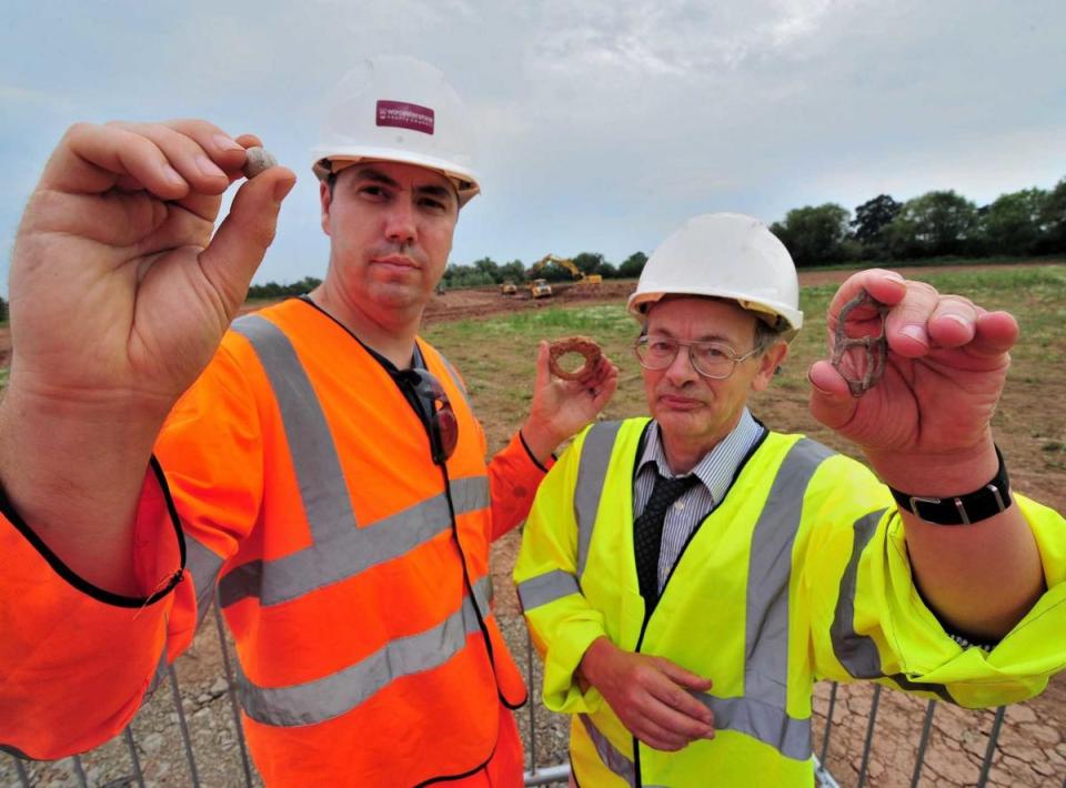  Archaeologists holding musket balls, trigger guards and belt buckles