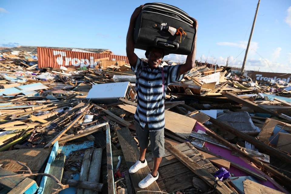  A man carries his belongings through the wreckage of destroyed buildings on Abaco Island