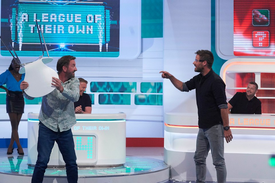  Lee Mack looks like he’s done with his teammates as he prepares to lob a chair at Jamie Redknapp