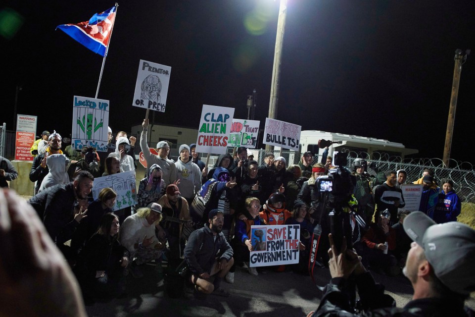  Clutching an array of signs, UFO-hunters mass outside the military facility