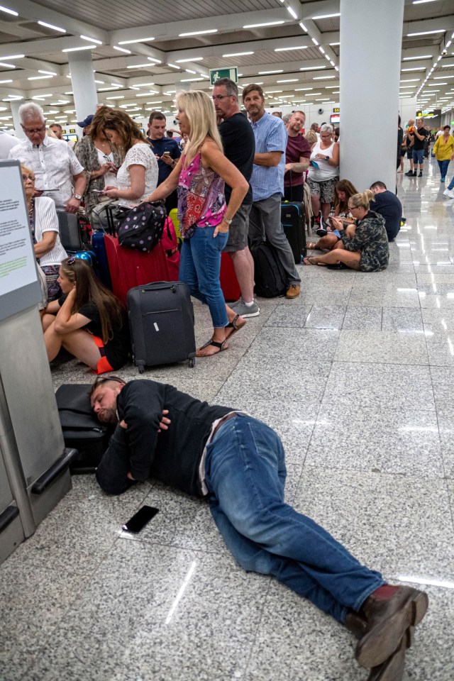 This passenger sleeps on the floor while waiting for answers at the airport in Palma de Mallorca in Majorca island