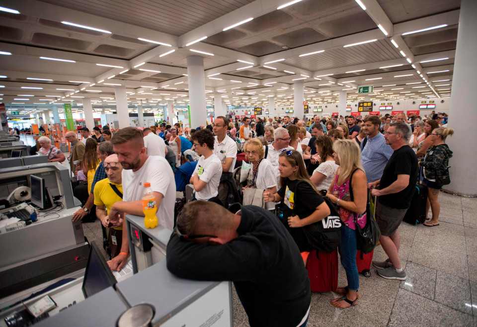 An exhausted passenger rests his head on the check-in desk at Son Sant Joan airport in Palma de Majorca