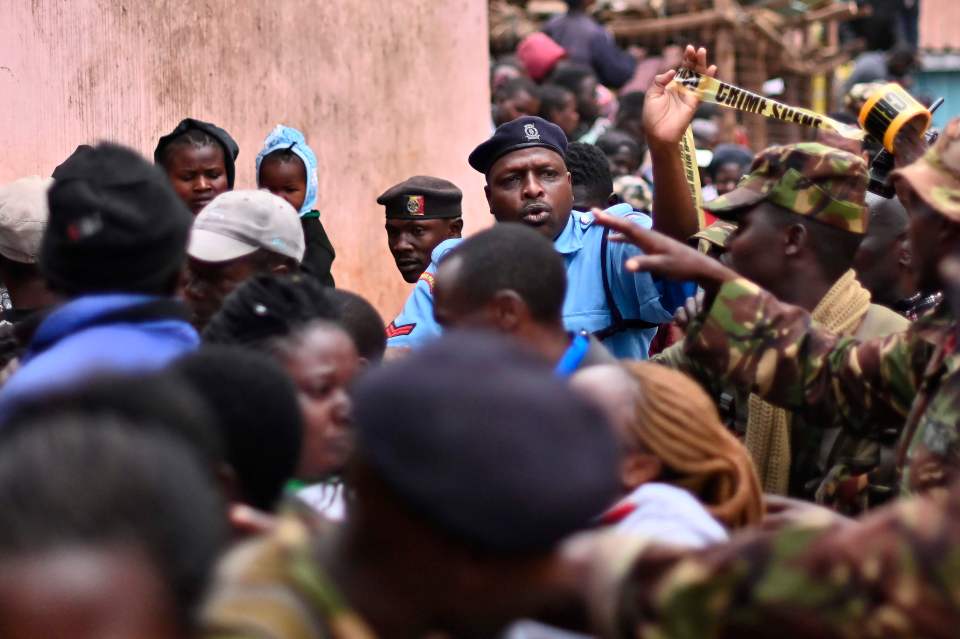  Police officers push back a crowd of onlookers as they secure the scene