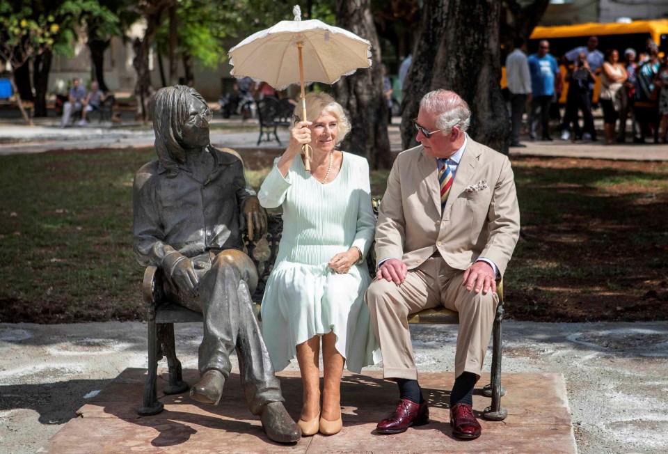 Camilla shades from the sun while sitting with Prince Charles