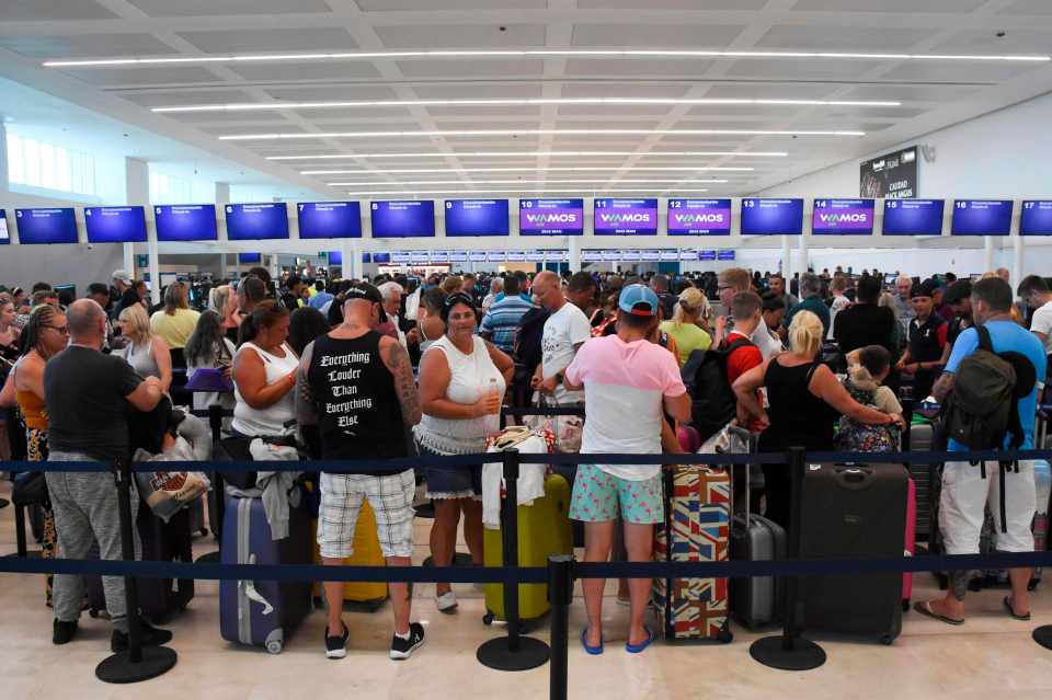 Passengers queue at the closed Thomas Cook check-in desk at the International Airport in Cancun, Mexico,