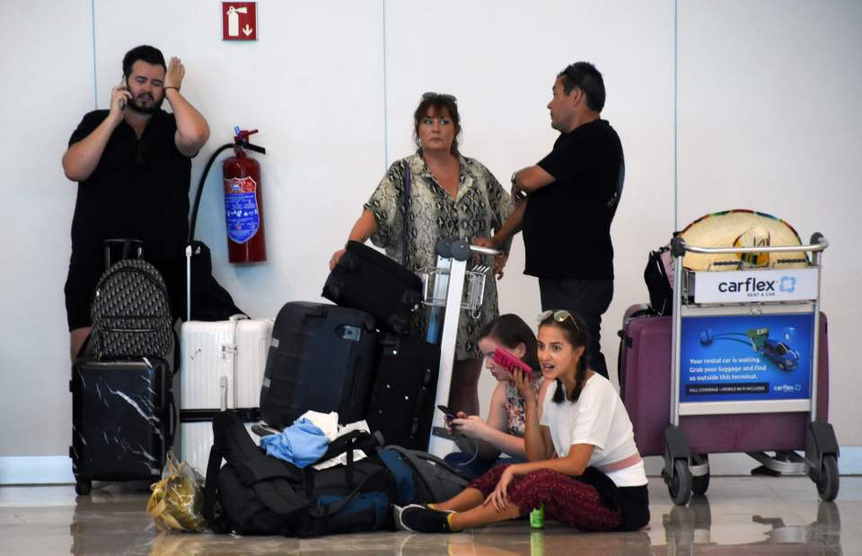 These holidaymakers appear stressed as they sit with their luggage in the airport in Cancun