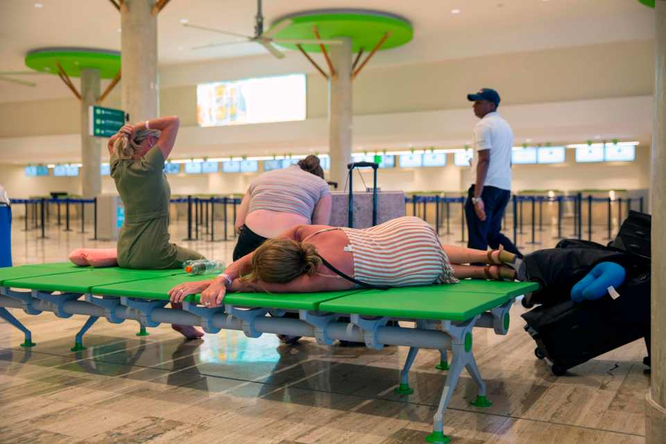 Passengers left stranded at Punta Cana's international airport, in the Dominican Republic get comfortable on the cots they will sleeping on overnight