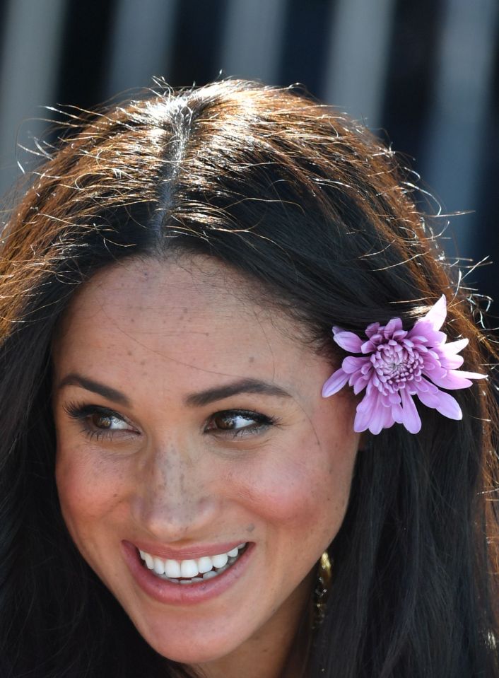  The royal puts a flower behind her ear after receiving flowers from members of the public