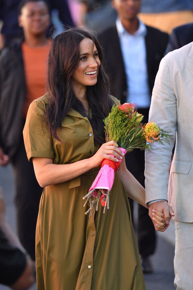  The Duchess of Sussex clutches a bouquet as she walks through the street with her husband