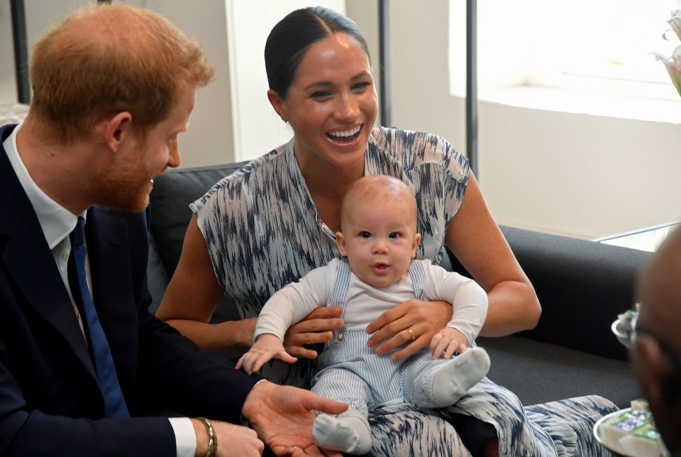  Archie was held by mum Meghan as Prince Harry played with his foot