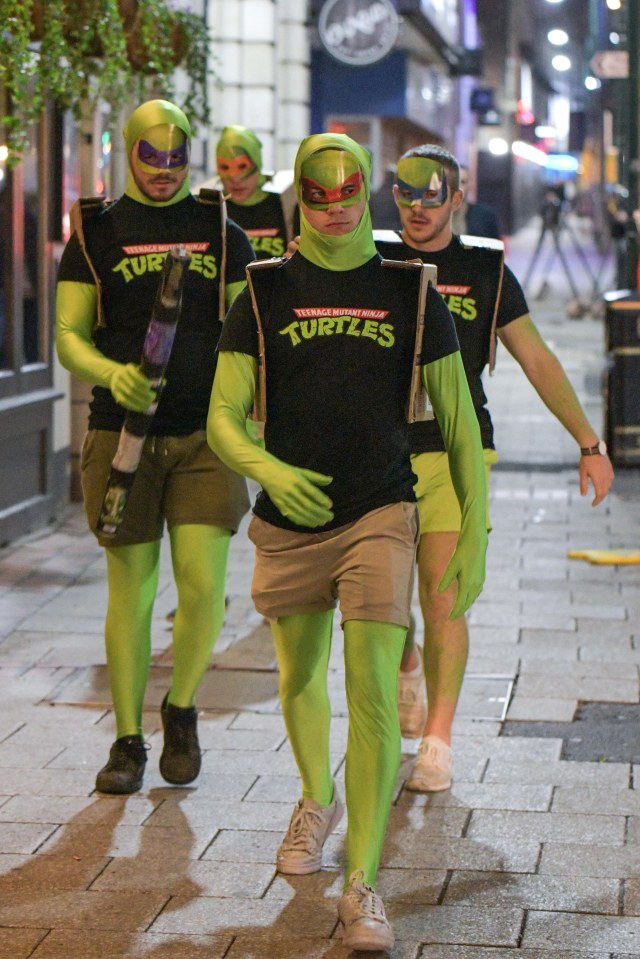  A group of four students stride down the street dressed as Teenage Mutant Ninja Turtles