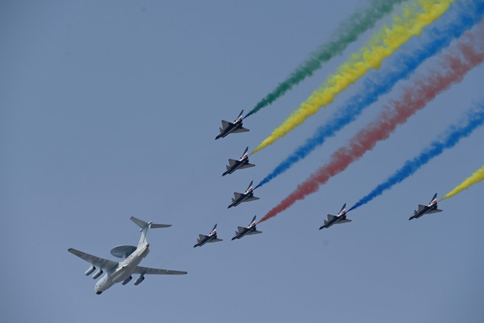 A formation of fighter jets trailing coloured smoke and led by a plane with a radar dish flew low over the capital