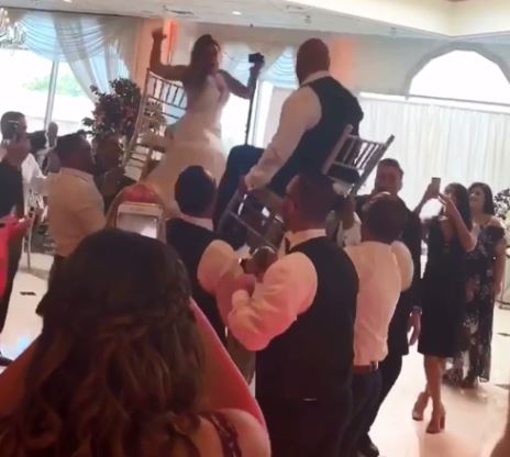 The bride is all smiles as she’s hoisted on to a chair opposite her husband