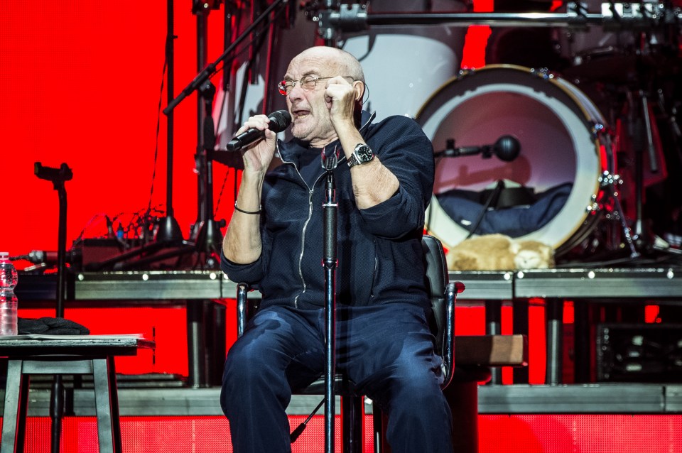 Phil sits down while performing live on stage