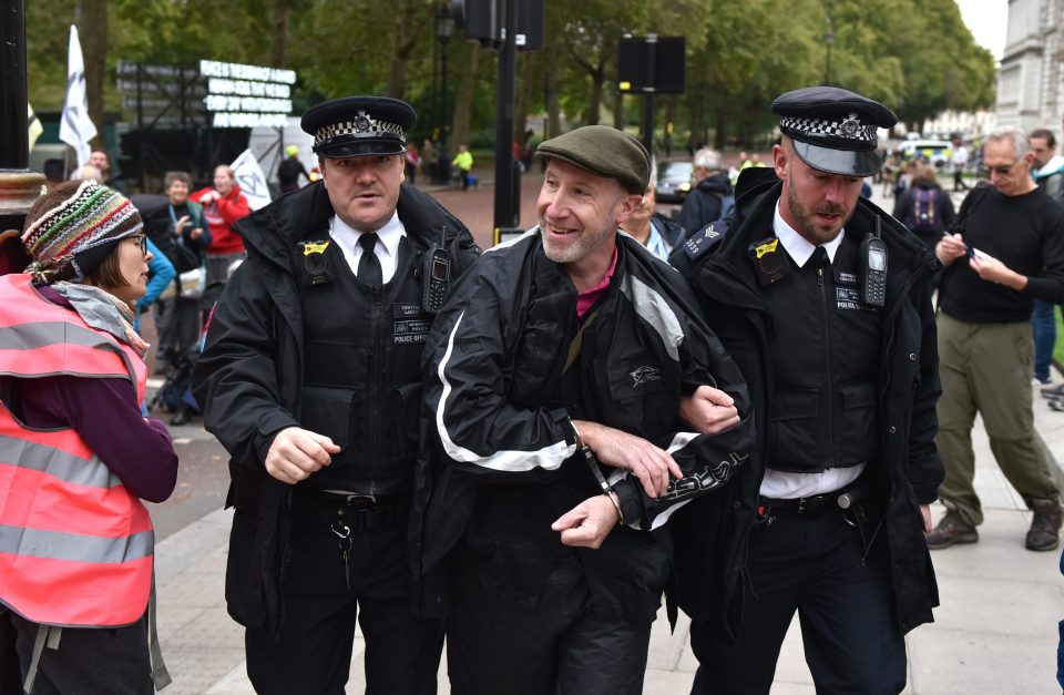  A protester smiles as he is arrested and led away by Police in Birdcage Walk in Westminster