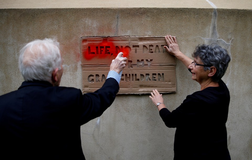  Phil Kingston, 83, sprays a stencil slogan on the wall of the building housing the Treasury during the Extinction Rebellion protest