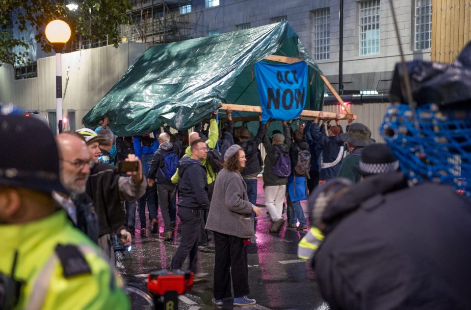  The green activists walk away under a tent structure after Police threatened to remove it