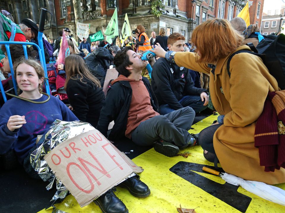  A protester, who has glued himself to the ground at Millbank, receives a drink from a fellow 'rebel'