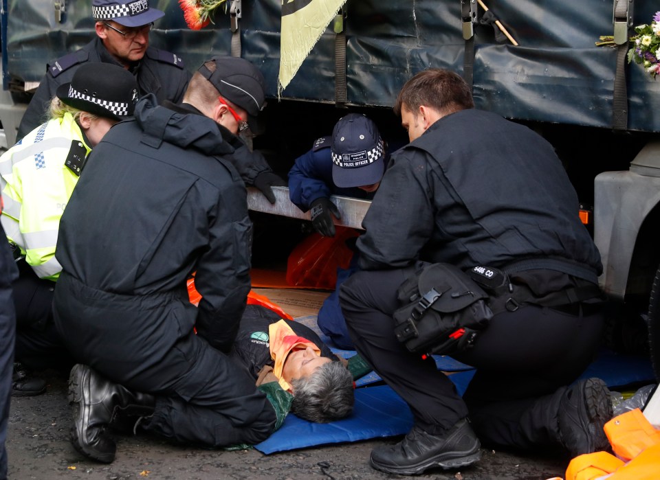  Police removal teams extract a climate change protester from underneath a lorry outside the Home Office