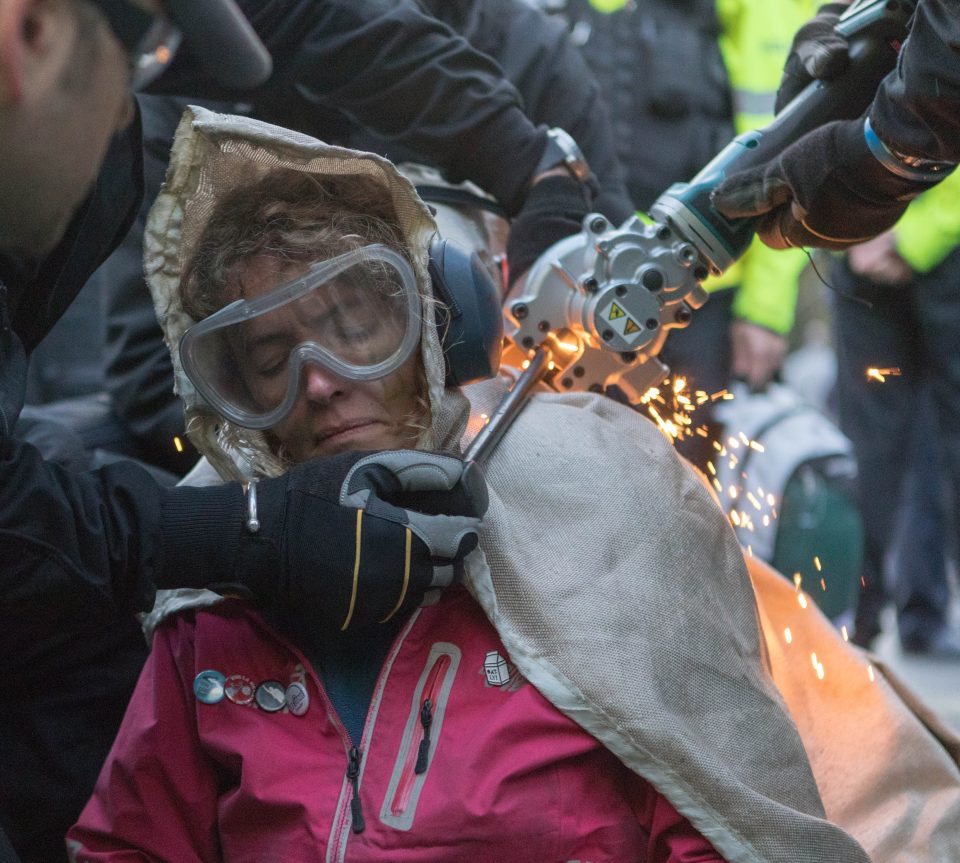  Police try to cut a woman chained to other eco-warriors in Whitehall yesterday evening