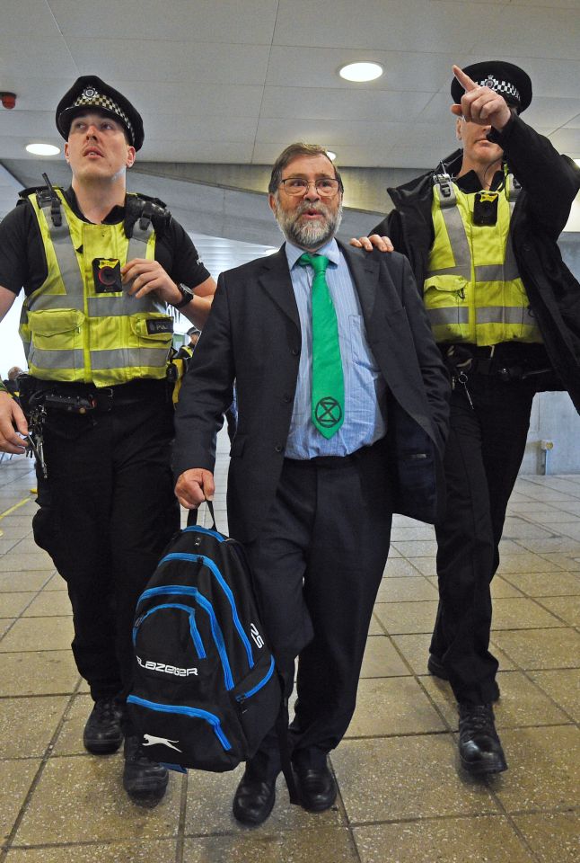  A man in an Extinction Rebellion tie is led away by officers