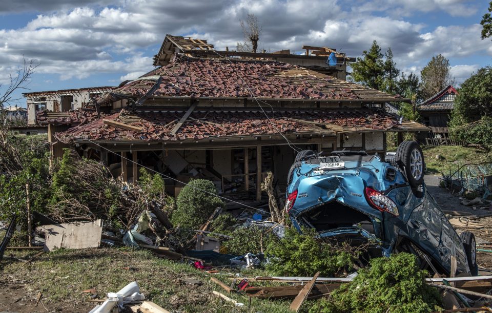  An upturned car lies next to a partially destroyed house after being hit by a tornado shortly before the arrival of Typhoon Hagibis