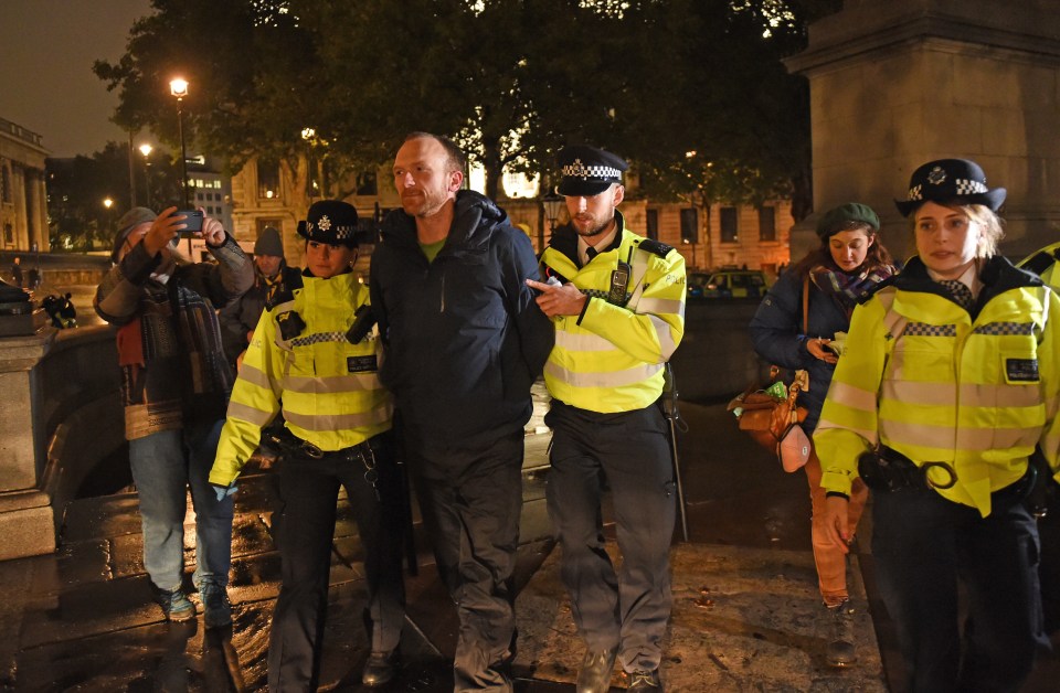 A protester is led away by police last night in Trafalgar Square