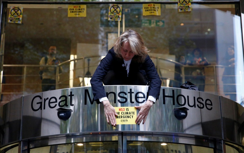 Co-founder of the Extinction Rebellion group, Gail Bradbrook, places a sign on top of the doorway into the Department of Transport