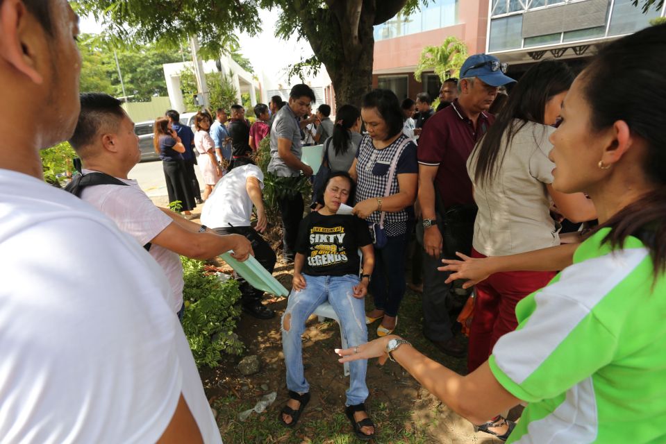  An office worker is helped by worried colleagues after she fainted at the height of the earthquake that hit Davao City, Philippines