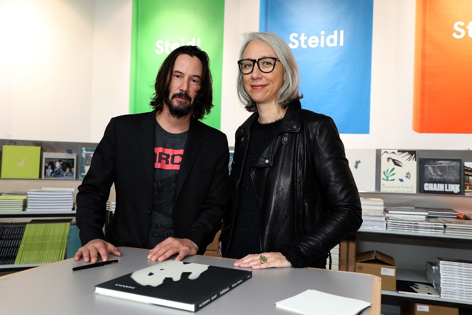 Keanu Reeves with Alexandra Grant posing with their 2016 book, Shadows, in Paris in 2017