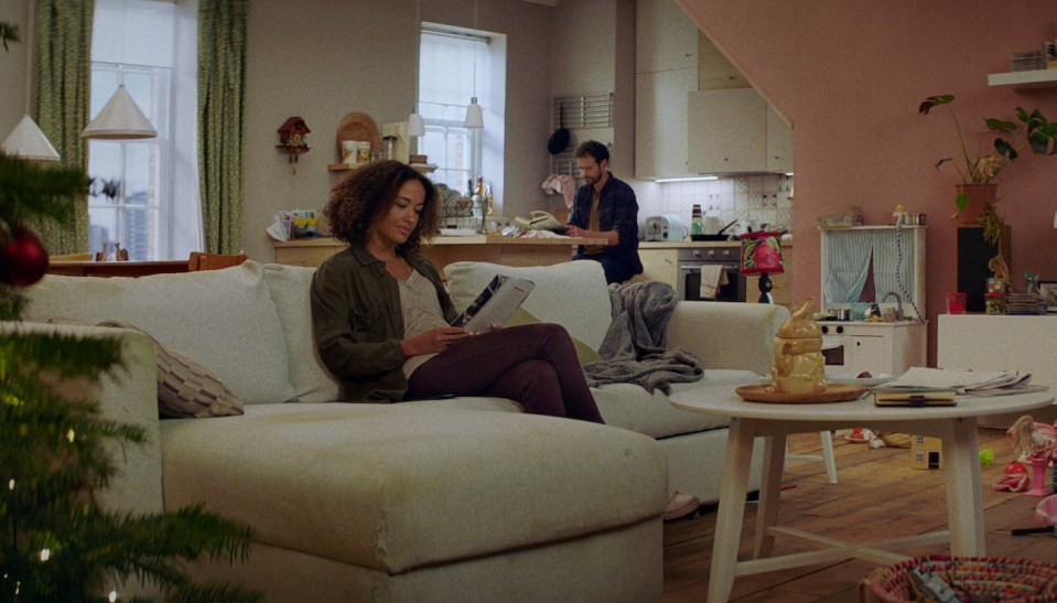 The family are in their drab living room at the beginning of the advert