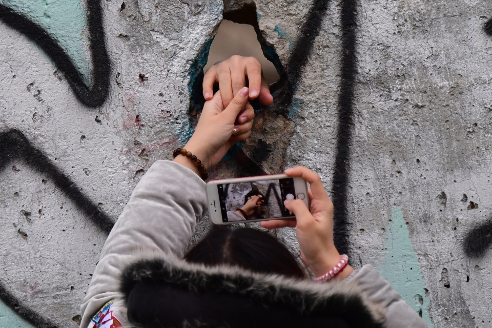  Two people reach through the wall which divided the city for 28 years