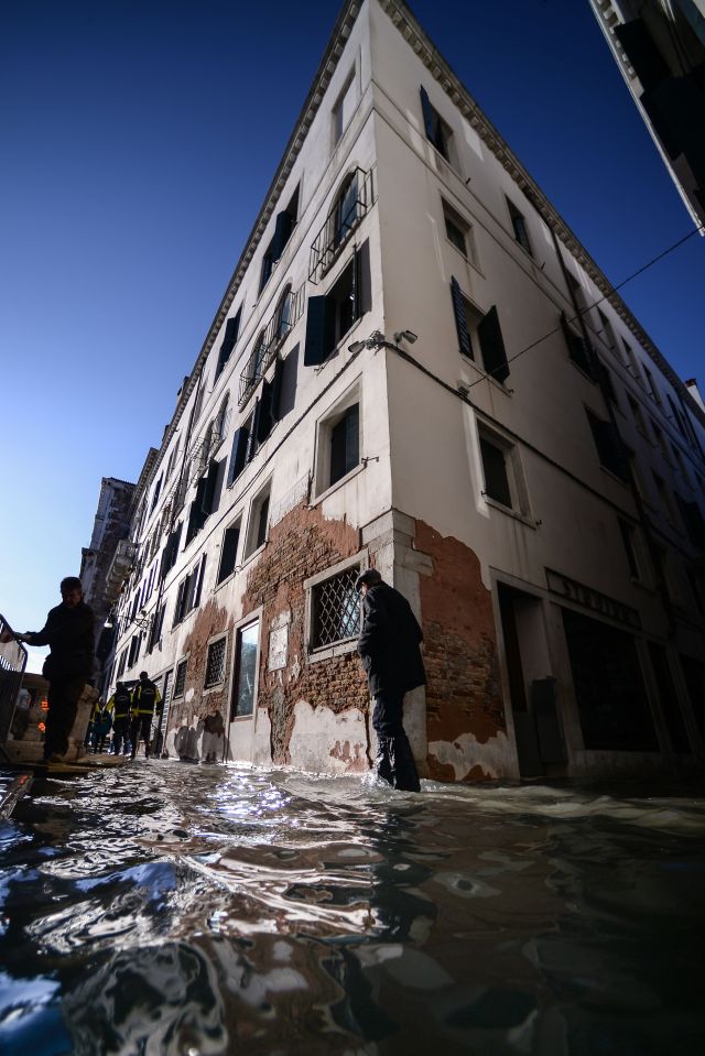  Residents walk through a flooded street in Venice